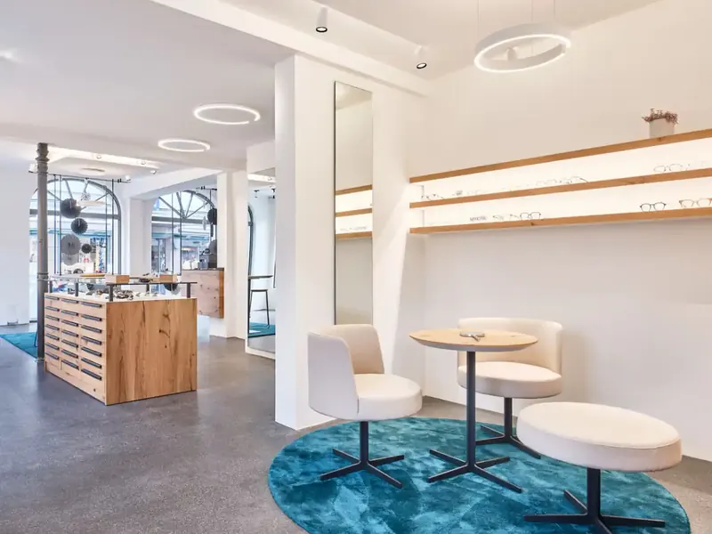Ladeneinrichtung eines Optikers mit Holztheke und Sitzgruppe
